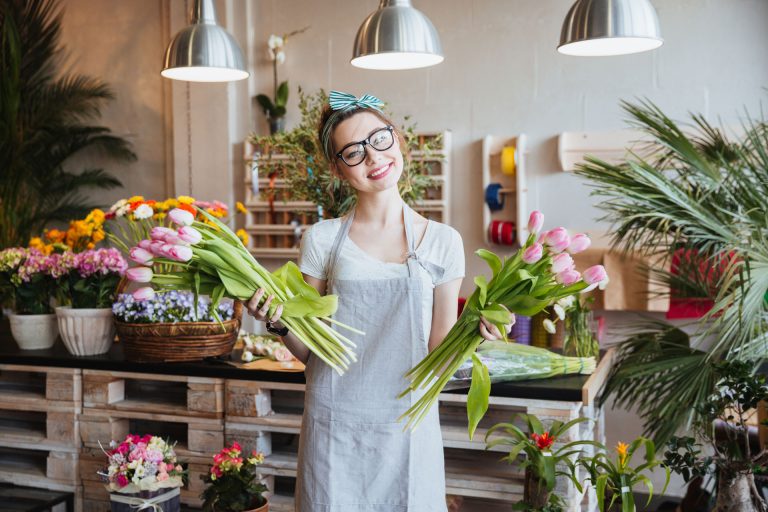 a woman holding a bunch of flowers in a flower shop.
